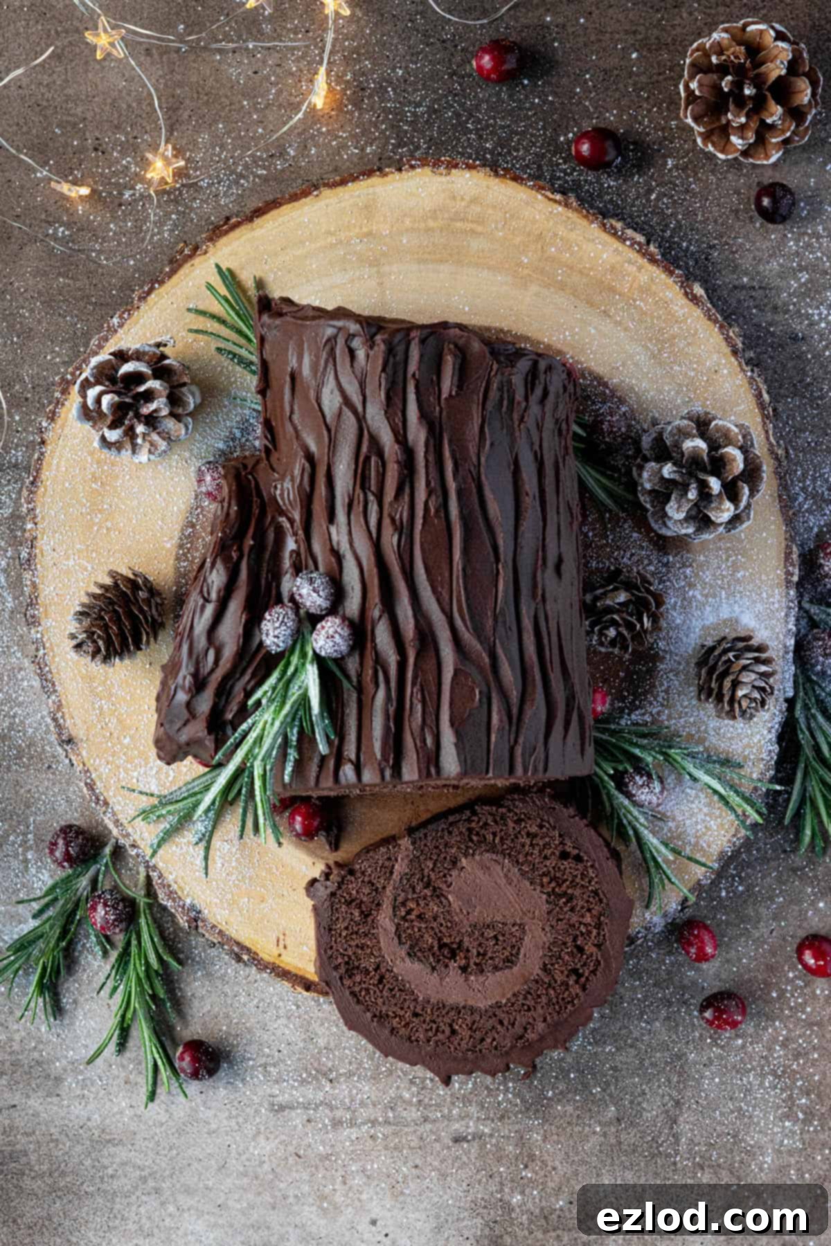 Plant-Based Chocolate Yule Log 15 A beautiful top-down shot of the sliced vegan yule log on a wooden board, surrounded by festive pine cones and twinkling Christmas lights, highlighting its holiday appeal.