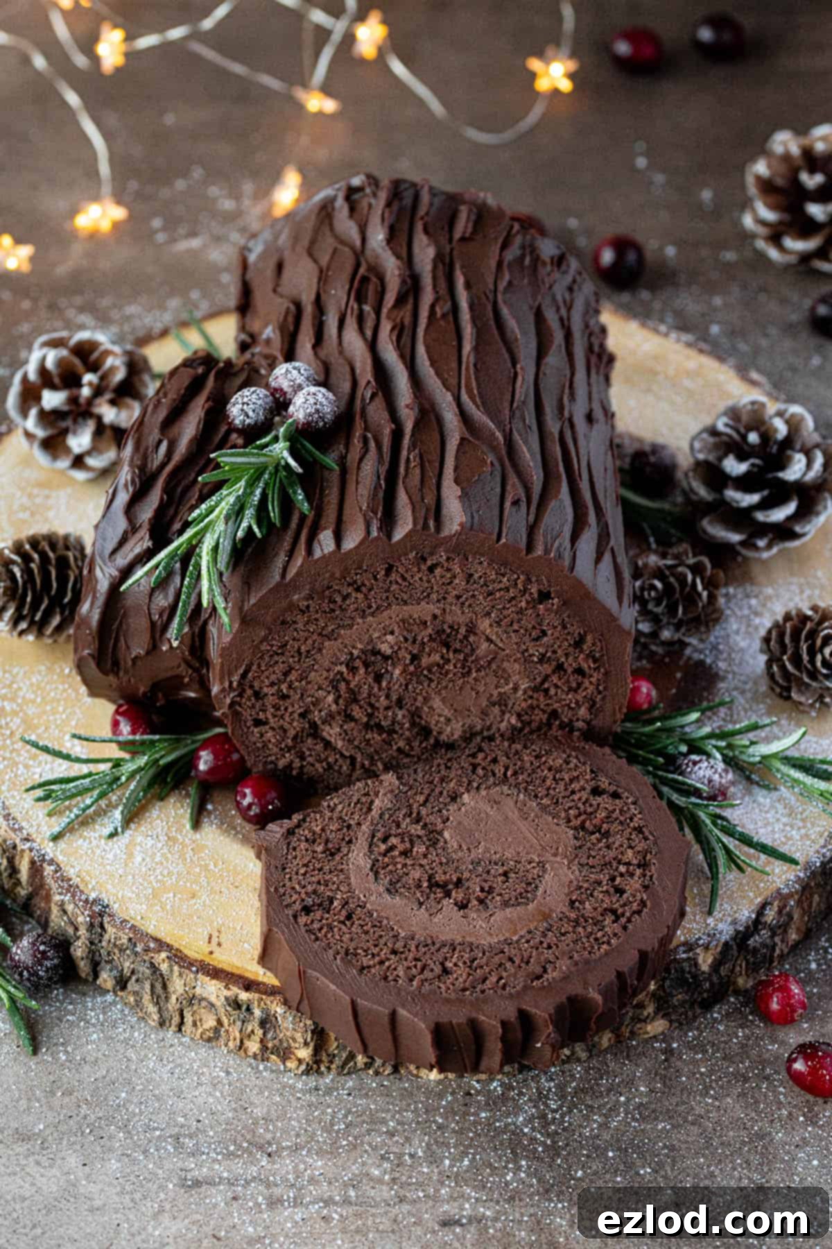 Plant-Based Chocolate Yule Log 16 The stunning vegan chocolate yule log displayed on a wooden board, beautifully adorned with pine cones and soft fairy lights, evoking a festive Christmas atmosphere.