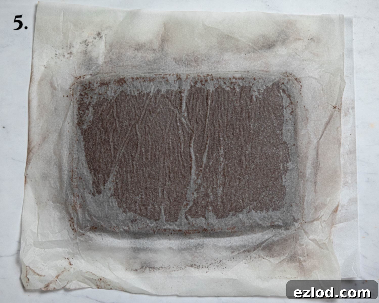 Plant-Based Chocolate Yule Log 9 Step 5: The hot cake has been inverted onto a cocoa-dusted sheet of baking paper and is left to cool, still with its original parchment attached to the bottom.