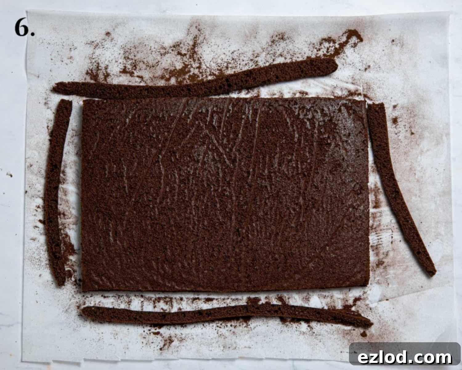 Plant-Based Chocolate Yule Log 10 Step 6: The cooled cake has its edges neatly trimmed with a serrated knife, preparing it for an even and crack-free roll.