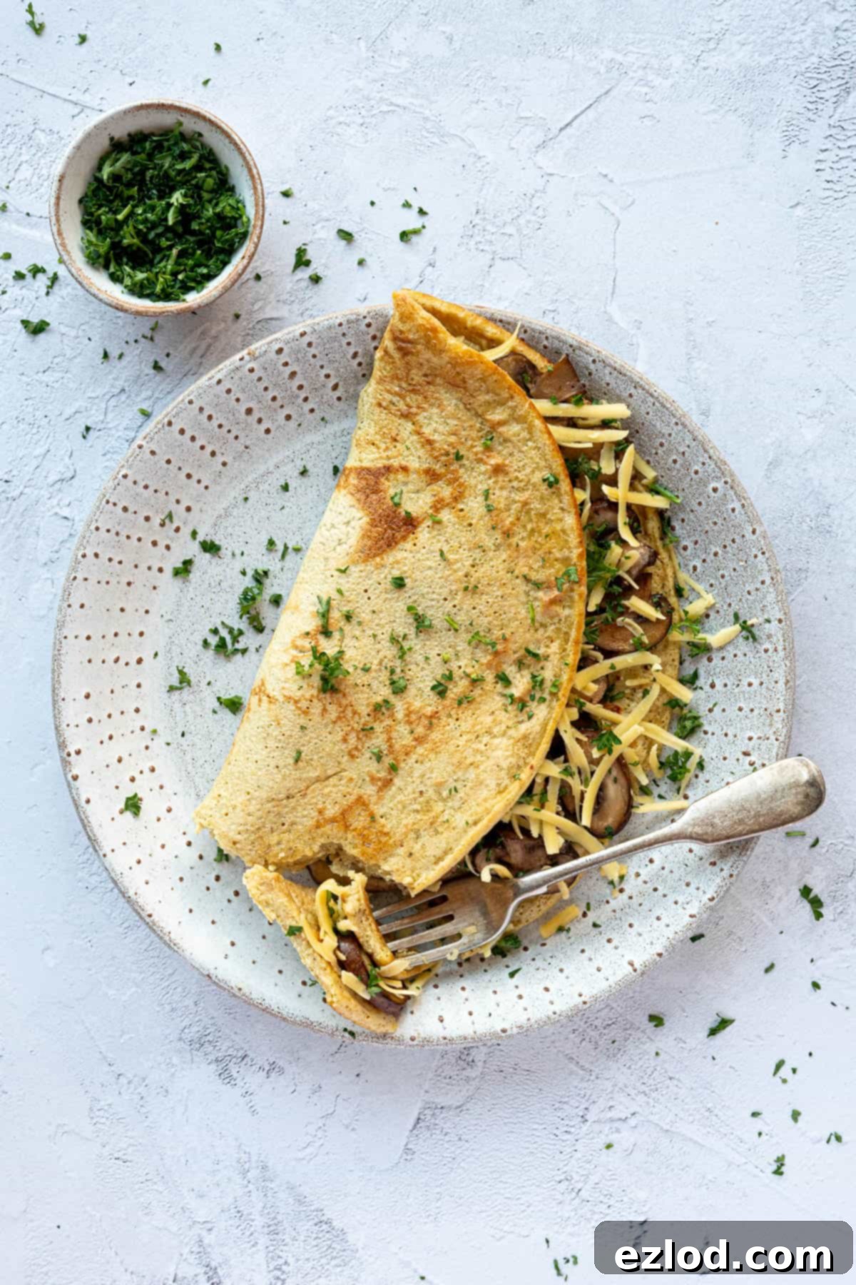 Golden Chickpea Fritters 8 A savoury chickpea pancake served on a white plate with a forkful removed, showcasing its fluffy interior and delicious filling.
