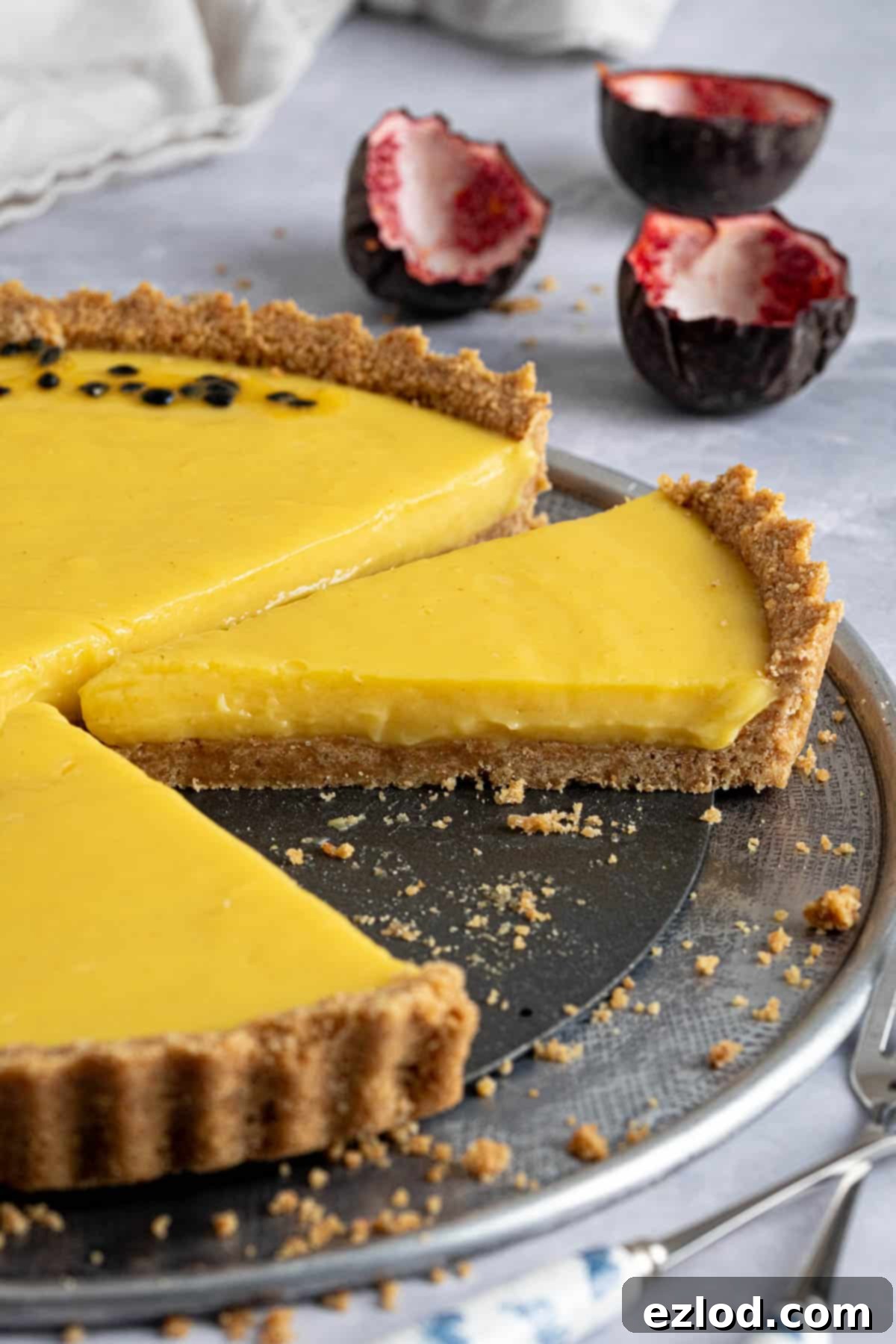 A vibrant close-up of a slice of vegan passion fruit tart, showing its smooth filling and crumbly base.