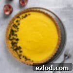 Vegan passion fruit tart on a metal plate with a couple of forks and some passion fruit shells.