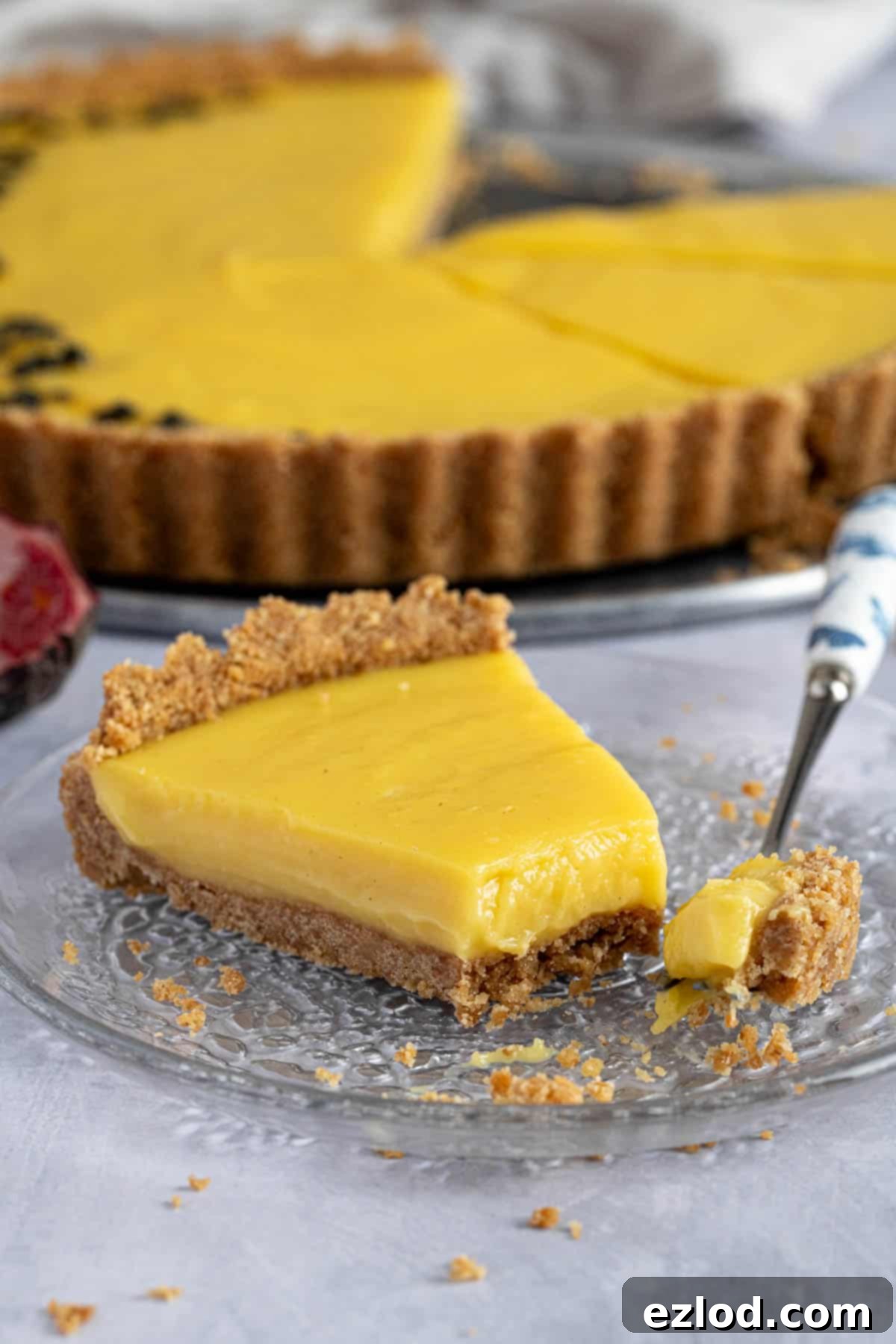 A perfect slice of vegan passion fruit tart, with a fork removing a creamy bite, highlighting its rich texture and vibrant color.