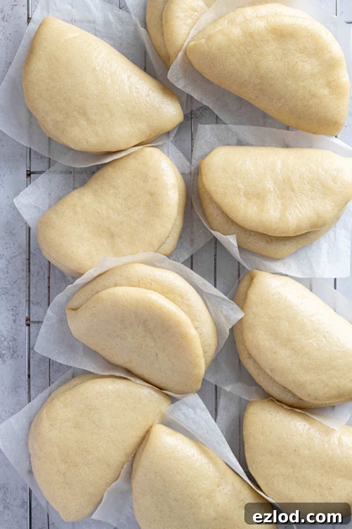 The soft, white bao buns arranged neatly on a wire cooling rack after steaming.