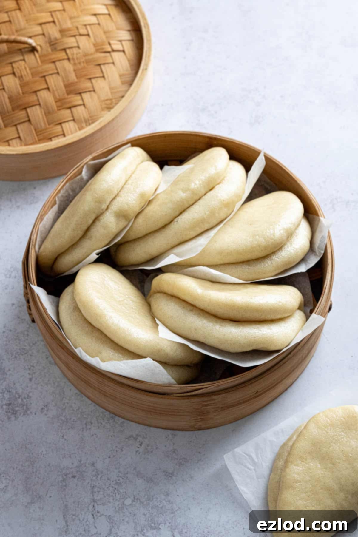 A pile of steamed bao buns stacked in a bamboo steamer, ready to be served.