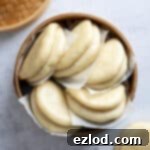 Bao buns on pieces of baking paper in a bamboo steamer.