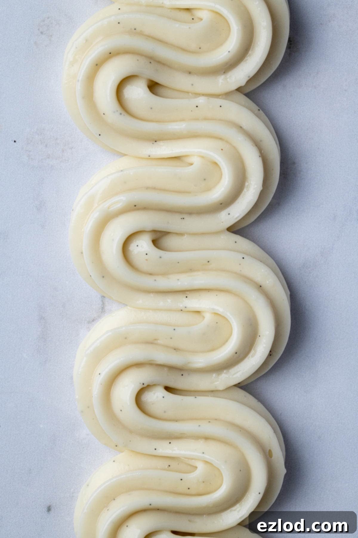 Beautiful swirls of piped vegan pastry cream on a clean marble surface.