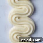 Swirls of piped vegan pastry cream on a marble surface.