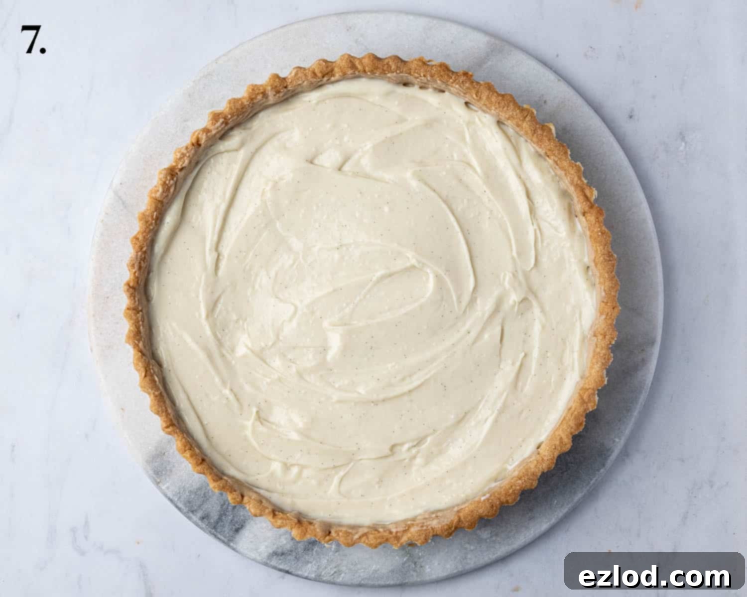 The tart shell generously filled with smooth, creamy vegan vanilla pastry cream, spread evenly to the edges.