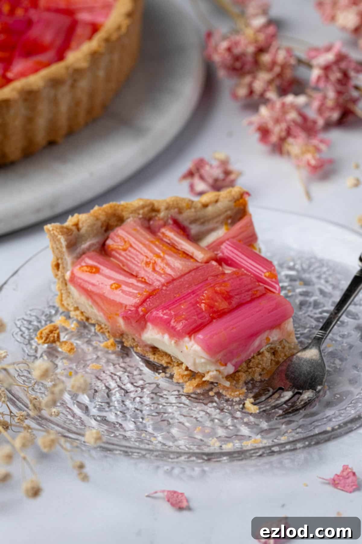 A beautiful slice of vegan rhubarb tart presented on a clear glass plate, ready to be enjoyed.