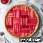 Vegan rhubarb tart on a marble board with dried flowers.