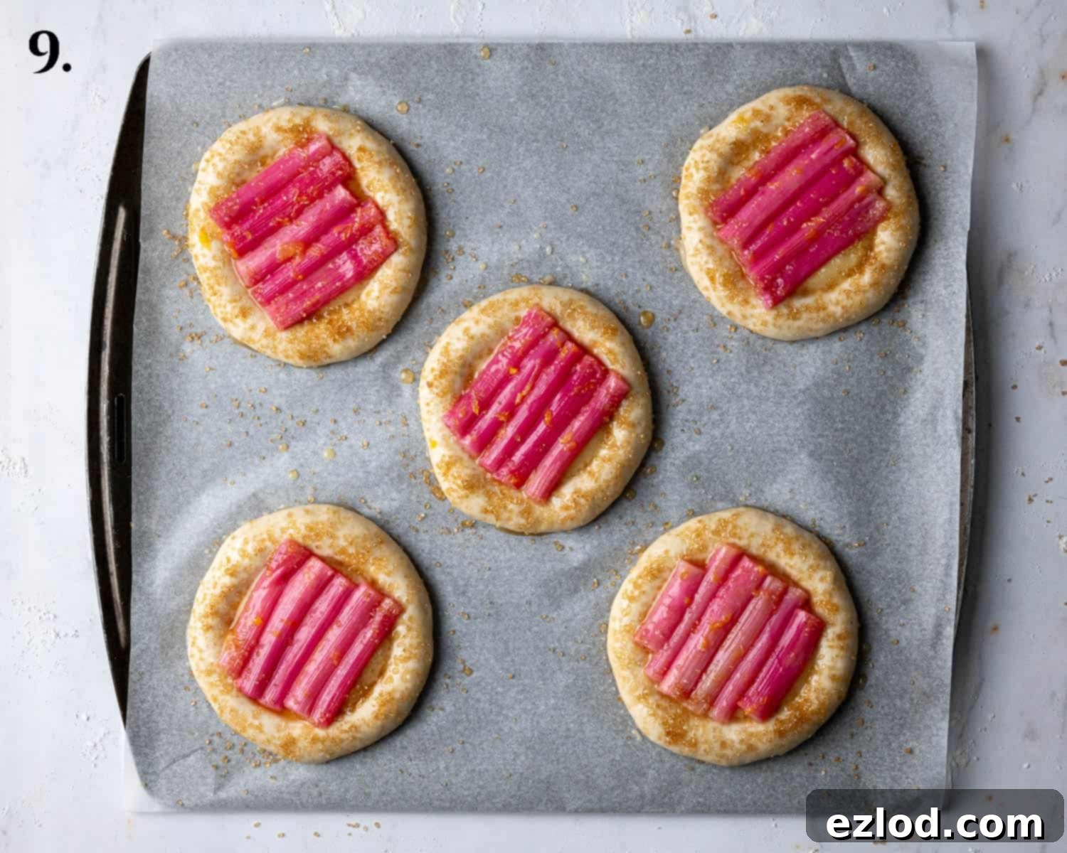 Step 9: The buns fully assembled with frangipane and rhubarb, brushed with glaze, and sprinkled with demerara sugar, ready for baking.