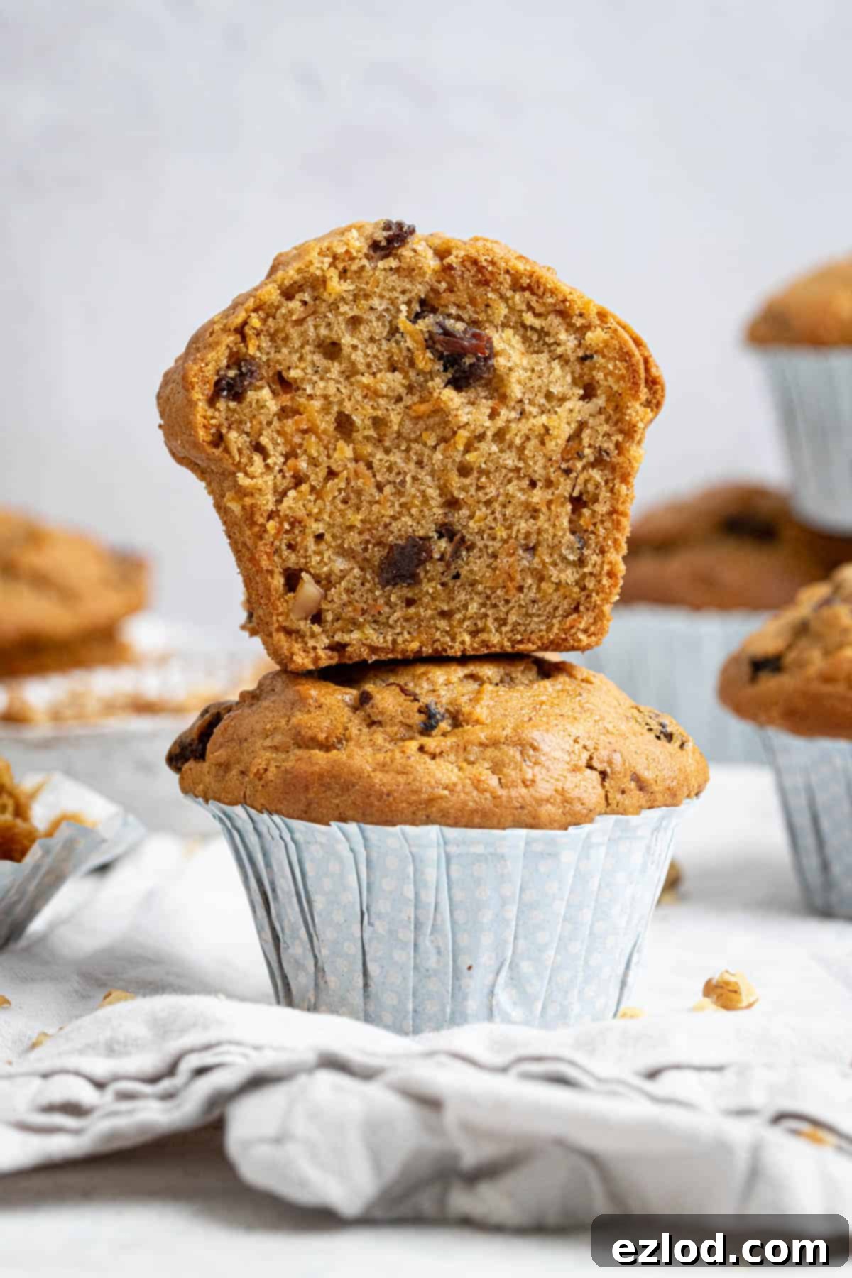 Perfectly Moist Vegan Carrot Muffins 4 Two vegan carrot muffins stacked on top of each other, the top one sliced din half.