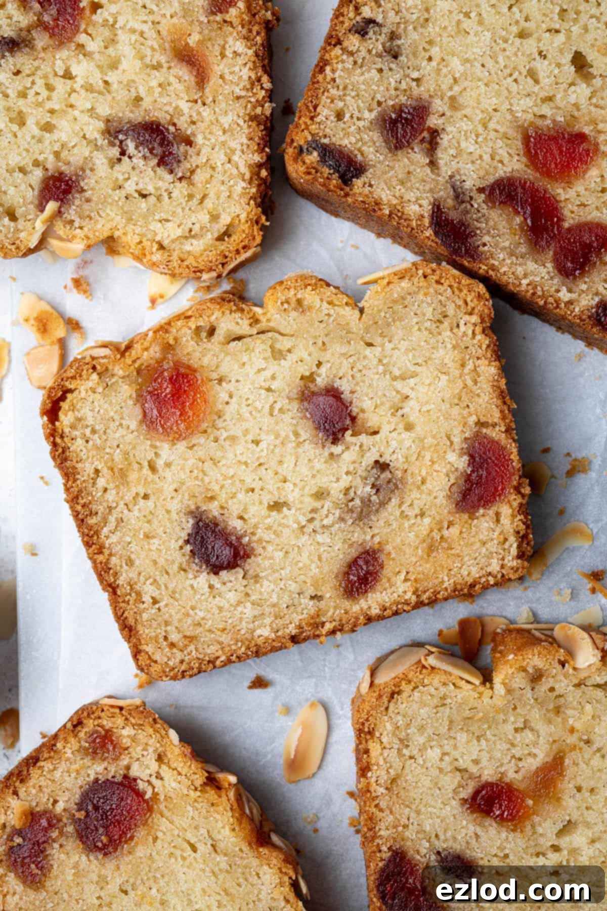 Multiple slices of the vegan cherry almond cake artfully arranged on a sheet of white baking paper, highlighting the cake's moist interior and cherry distribution.