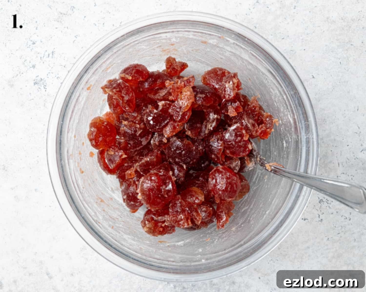 A bowl filled with vibrant glacé cherries, meticulously prepared by rinsing, drying, and lightly coating with flour to prevent them from sinking in the cake batter.
