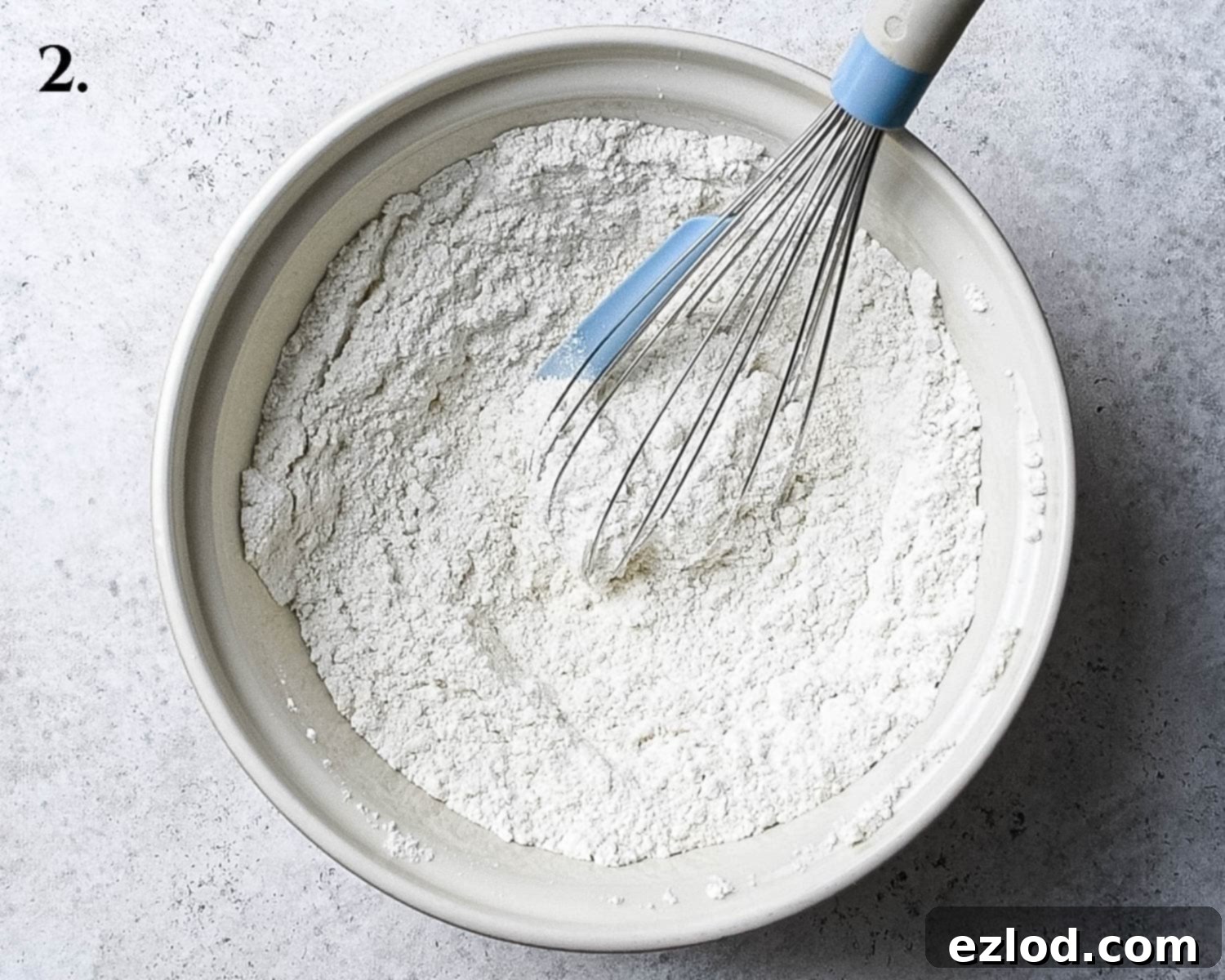 A large mixing bowl containing all the perfectly combined dry ingredients, including plain flour, cornflour, ground almonds, sugar, baking powder, baking soda, and salt, ready for the wet ingredients.