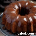 Vegan banana bundt cake with chocolate glaze on a metal plate.