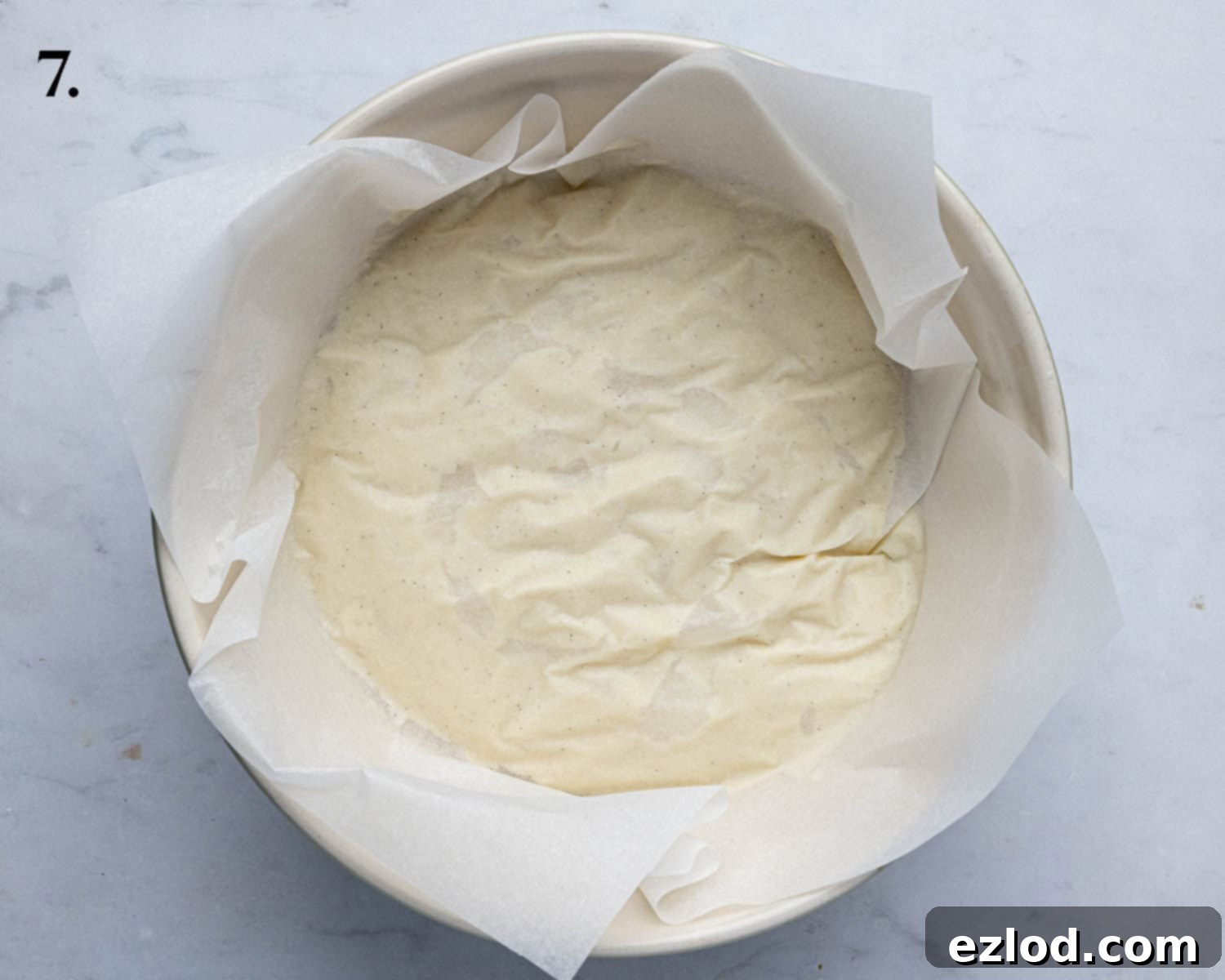 The cooked pastry cream neatly covered with baking paper pressed directly onto its surface, ready for chilling in the refrigerator.