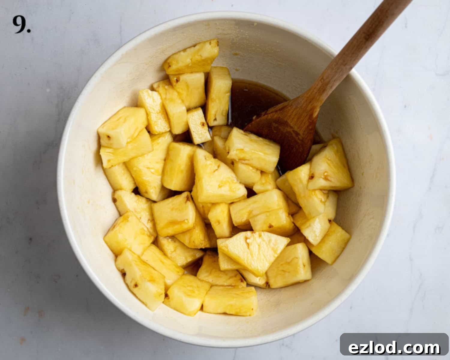 Fresh pineapple chunks generously coated in a mixture of brown sugar, rum, and lime juice in a bowl.