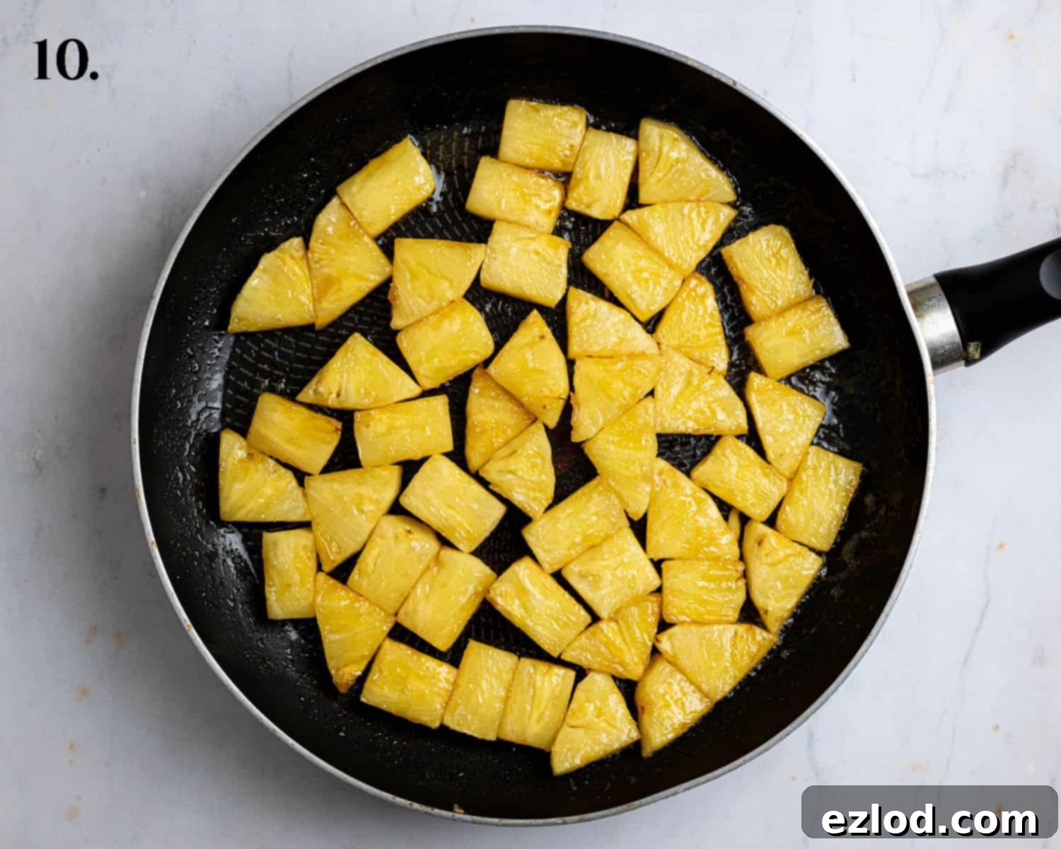 Golden-brown, pan-fried pineapple pieces cooking in a large non-stick frying pan.