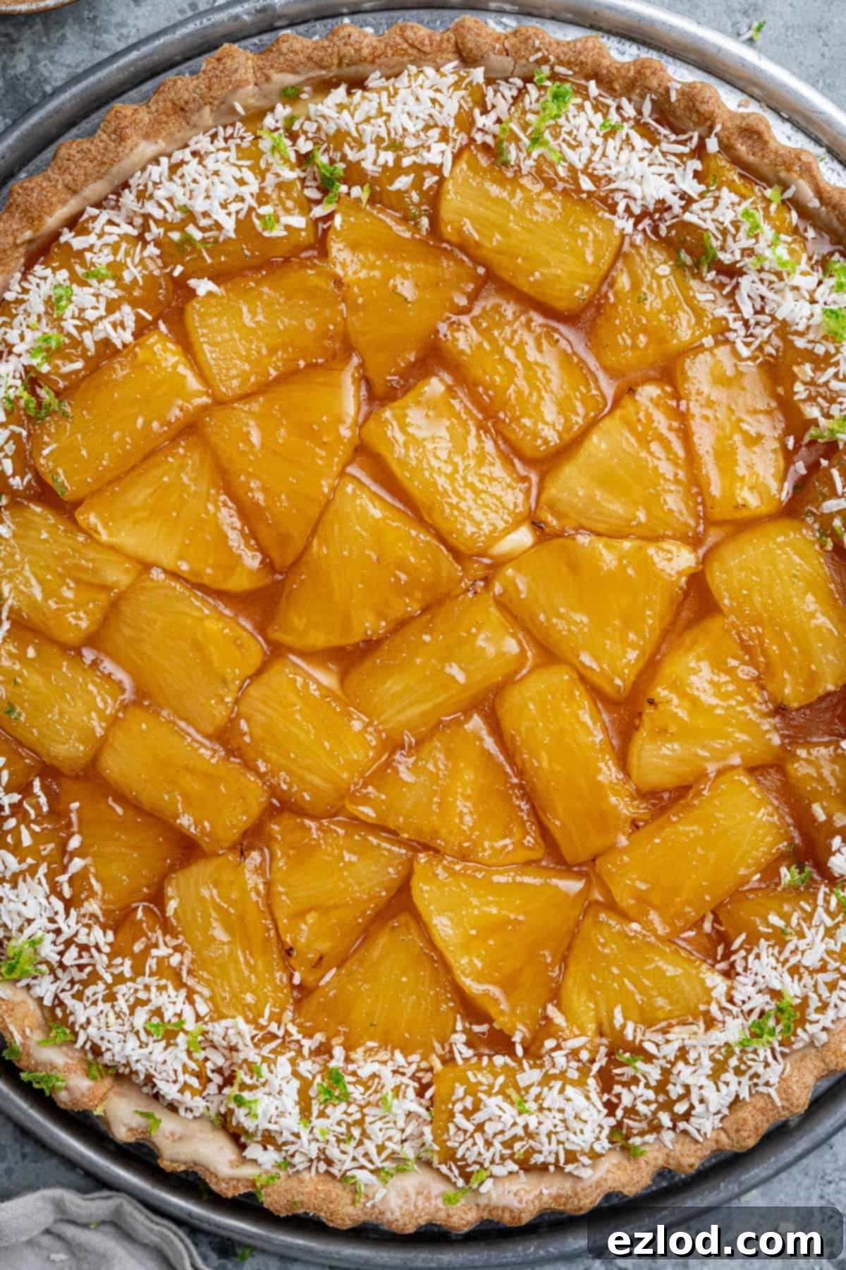 A close-up shot of the assembled caramelised pineapple coconut tart, showing the beautifully arranged pineapple pieces atop the creamy filling.