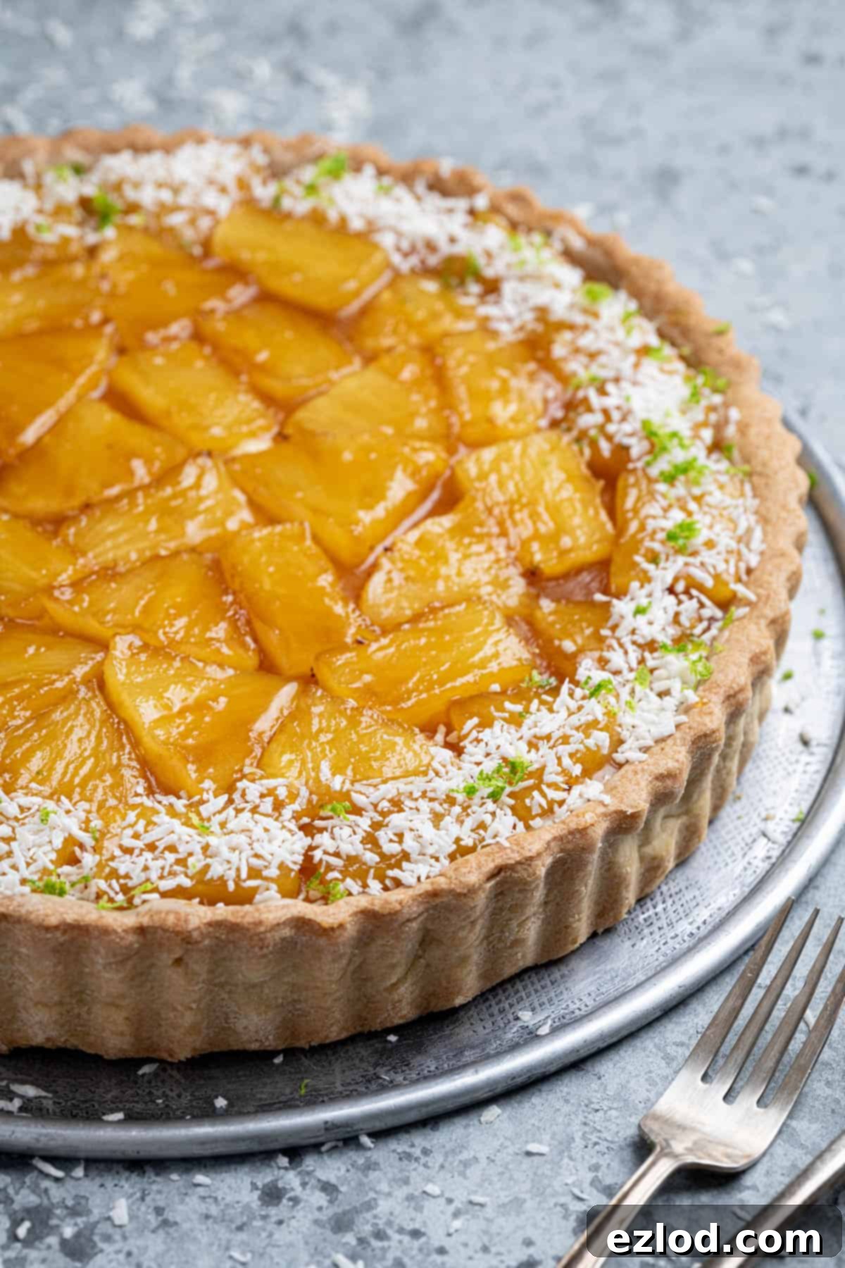 A close-up side view of the beautifully layered vegan caramelised pineapple coconut tart, showcasing its crisp crust and creamy filling.