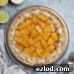 Caramelised pineapple coconut tart on a metal plate with forks, sliced limes and a bowl of desiccated coconut.