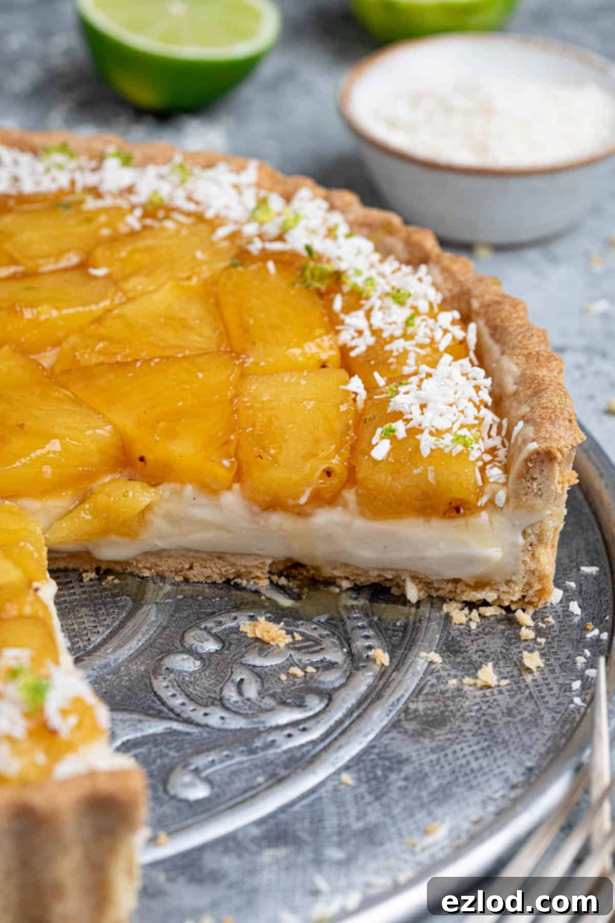 A close-up shot of a single slice of Caramelised Pineapple Coconut Tart, showing the layers of crisp pastry, creamy filling, and golden pineapple.