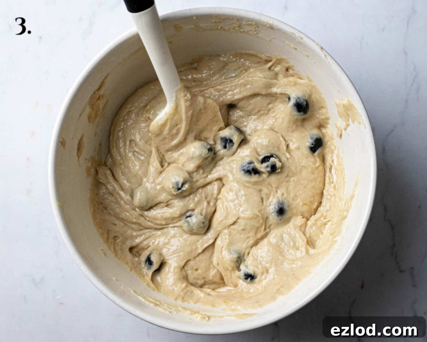 Step 3: The completed cake batter, smooth and lightly studded with blueberries, in a mixing bowl.