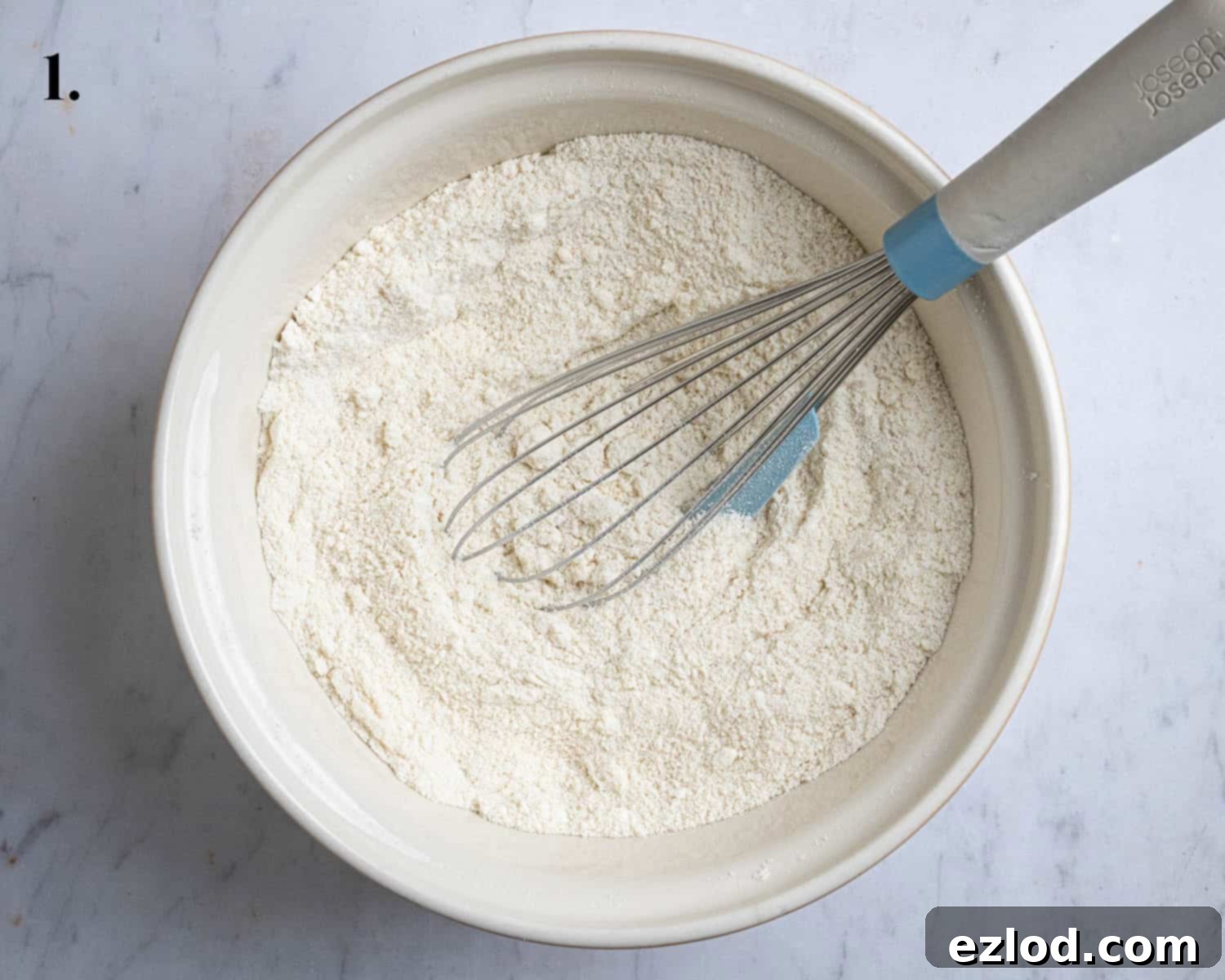 Step 1 in the baking process, showing all the dry ingredients for the lemon elderflower almond pudding mixed together in a large white bowl.