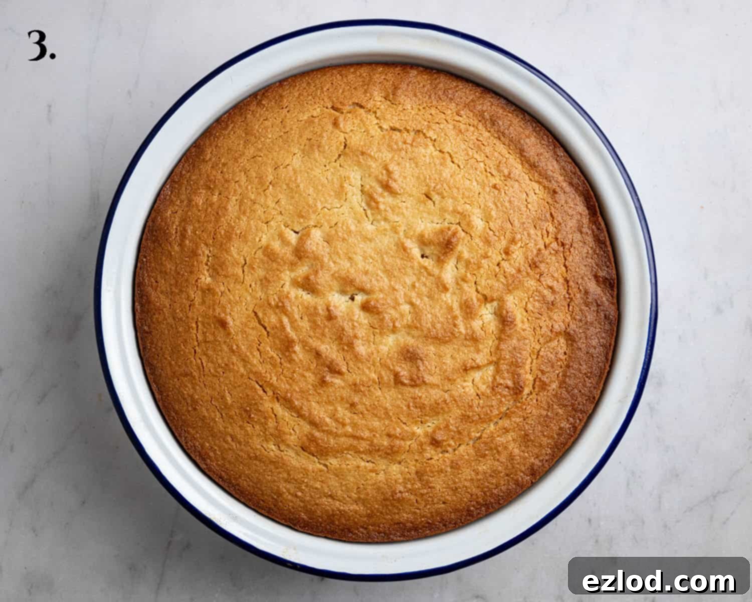 Step 3: The perfectly baked lemon elderflower almond pudding, golden brown and puffed up, sitting in a round baking dish.