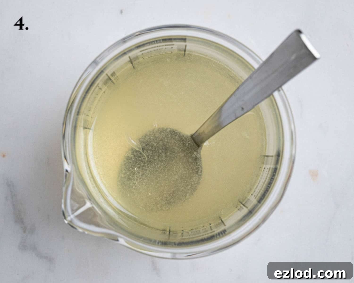 Step 4: The vibrant elderflower and lemon juice drizzle, ready to be poured, contained within a small glass jug.