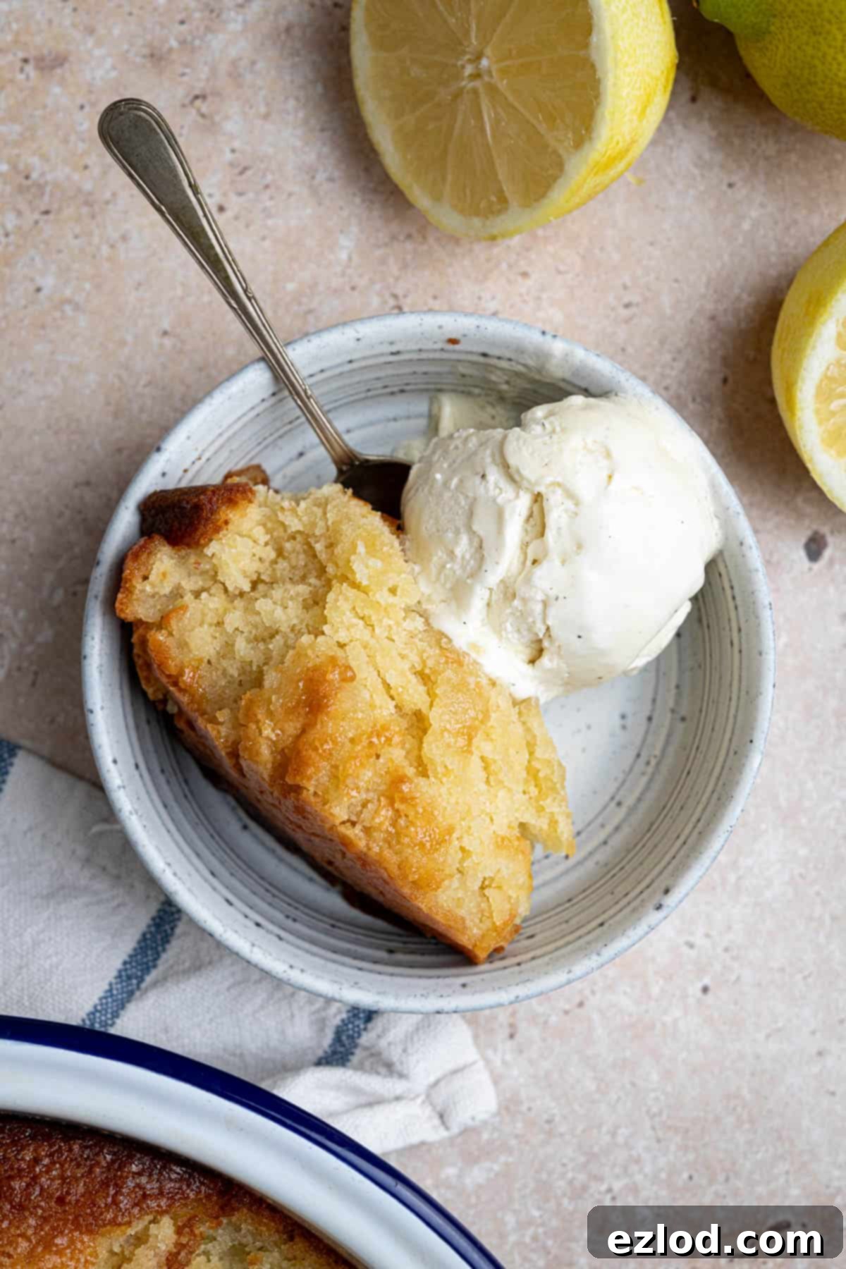 A tantalizing spoonful of lemon elderflower almond pudding served in a small bowl, accompanied by a scoop of creamy vanilla ice cream.