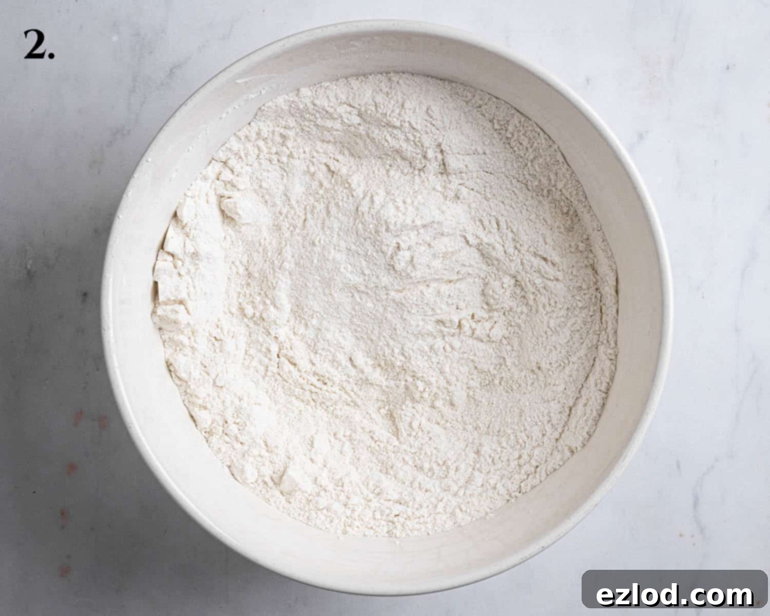 Step 2 of making vegan Boston cream pie: A bowl containing the carefully whisked dry ingredients, ready for the wet mixture.