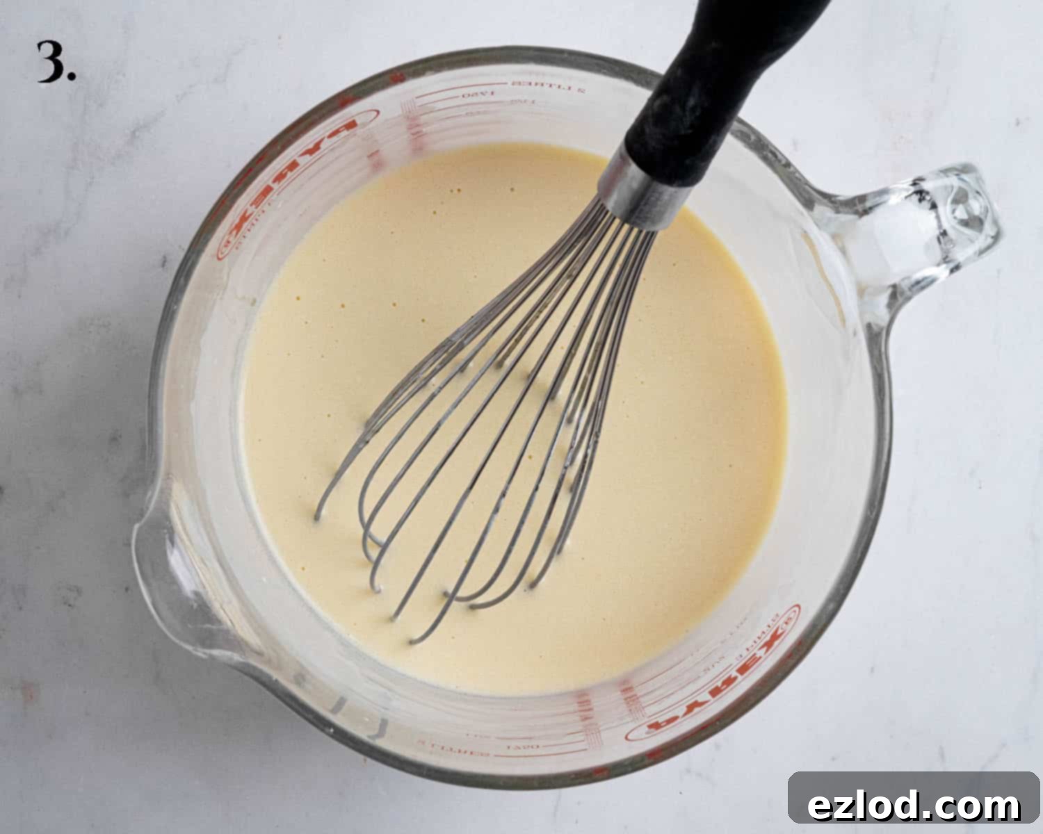 Step 3 of making vegan Boston cream pie: A jug filled with the thoroughly mixed wet ingredients, showing a smooth, cohesive liquid.