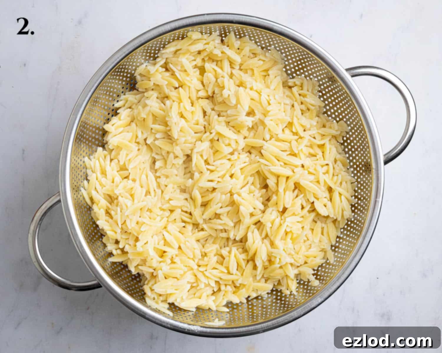 Step 2: Cooked and drained orzo pasta, ready to be added to the sauce.