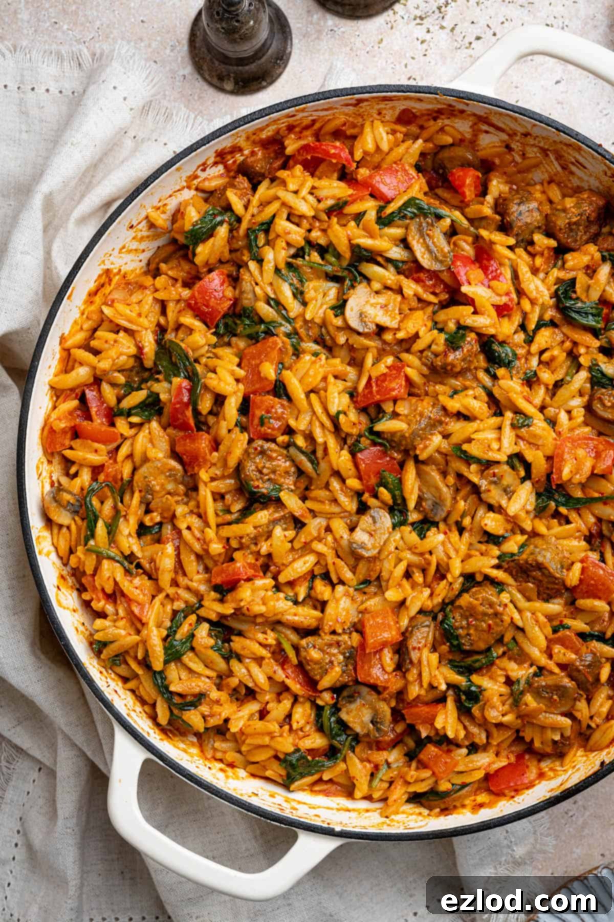 Close up shot of vegan spicy sausage orzo mixed in a pan, showing the sauce and ingredients.