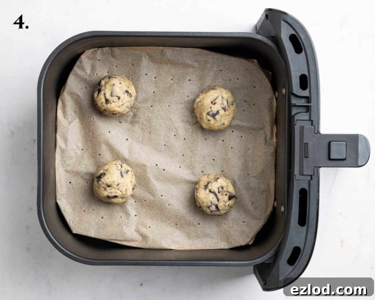 Step 4: Portioning the cookie dough into balls and placing them in a lined air fryer basket, spaced apart.