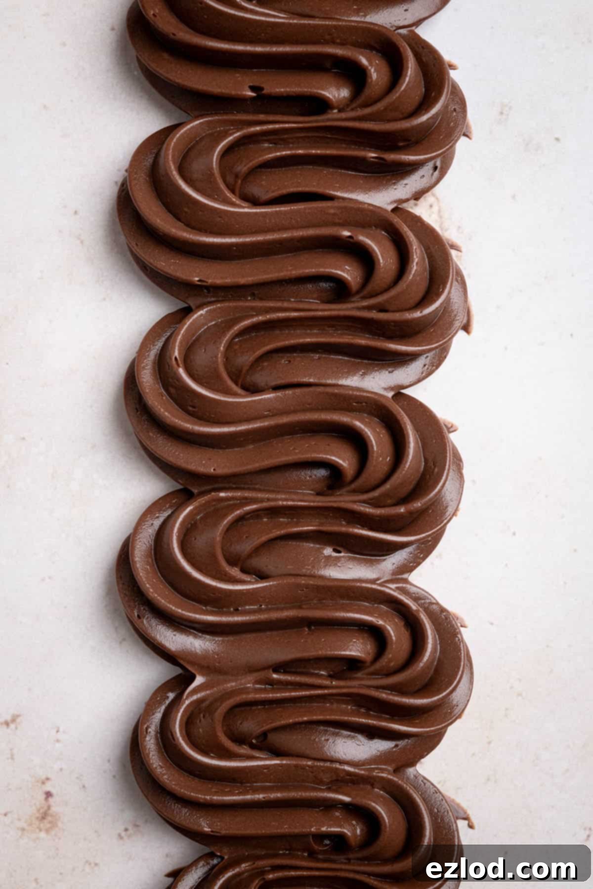 Swirls of vegan chocolate pastry cream piped on a marble surface.