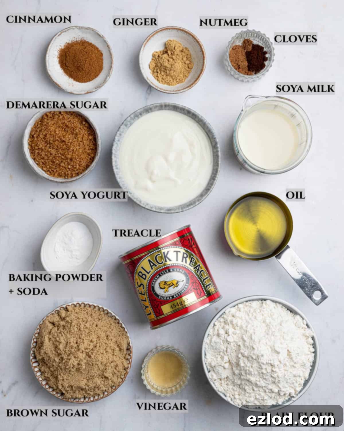 Ingredients for vegan gingerbread muffins laid out in bowls, including flour, sugar, molasses, spices, and plant milk.