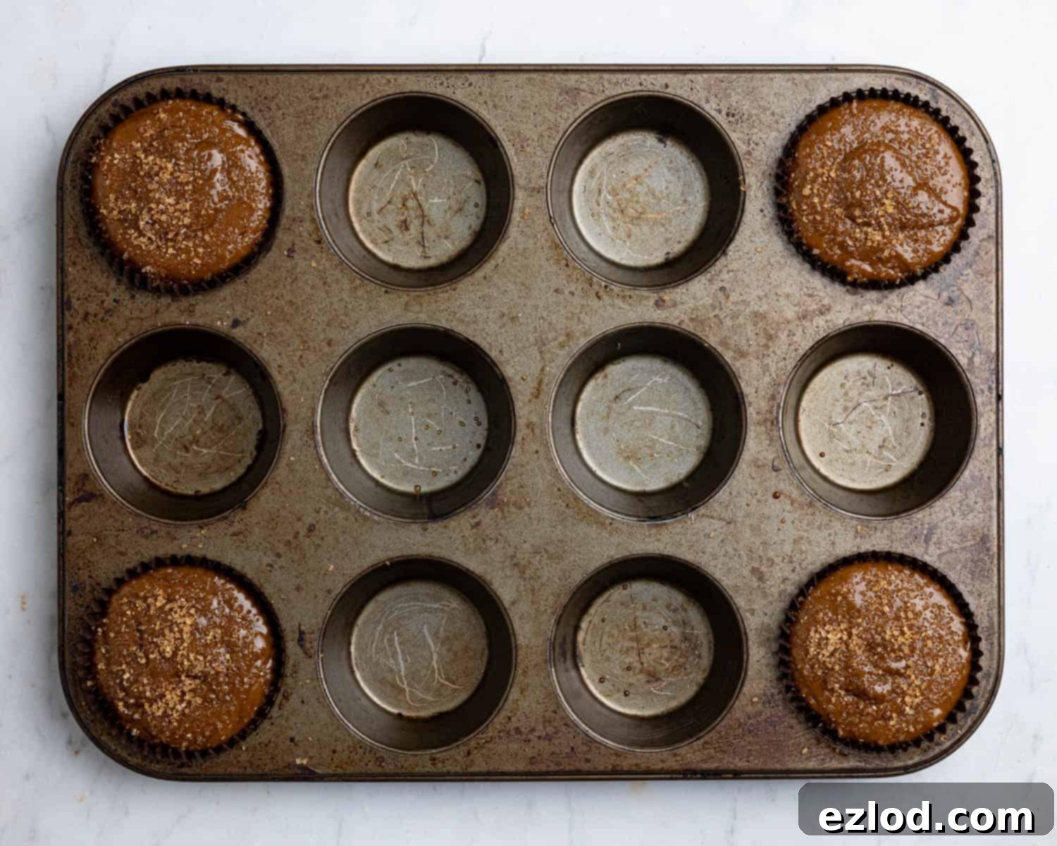 Step 3: Muffin cases filled with gingerbread batter and sprinkled with demerara sugar, ready for baking.