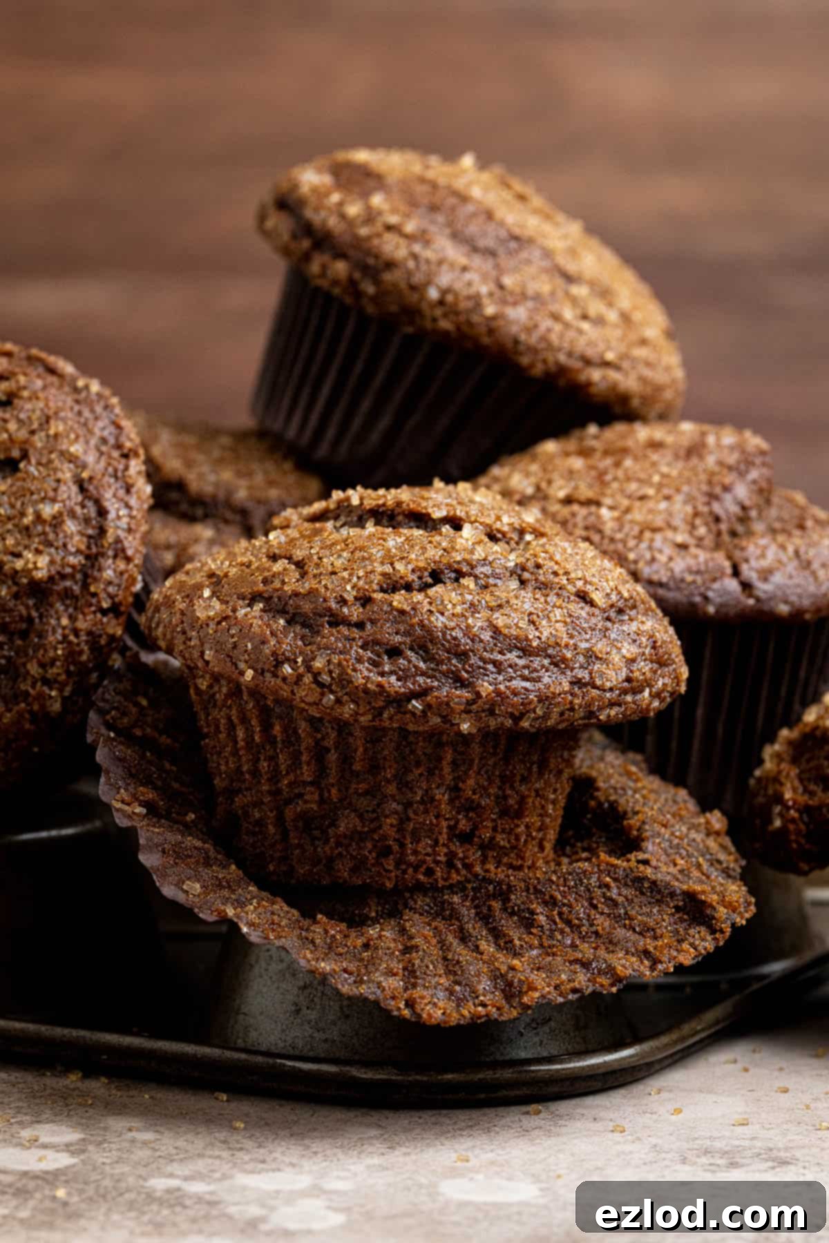 A stack of golden brown vegan gingerbread muffins on top of an empty muffin pan.