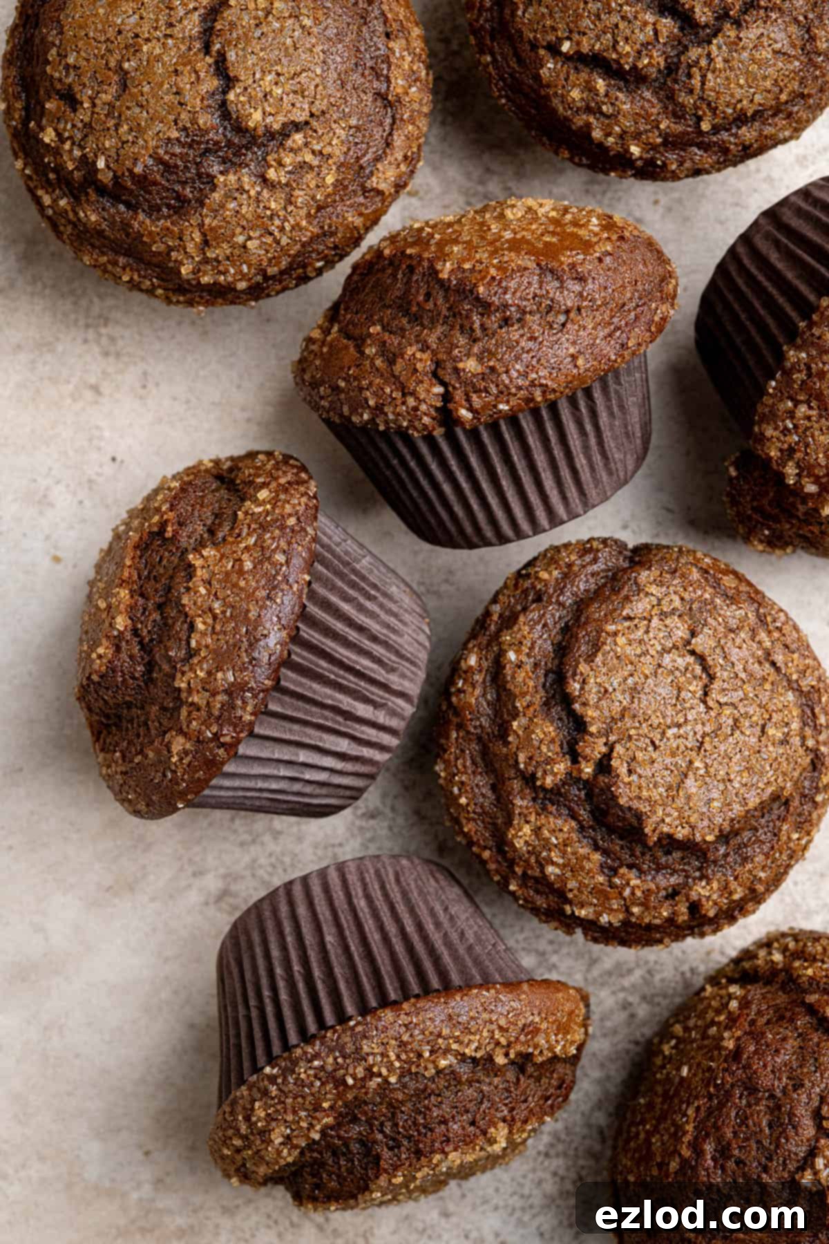 A collection of vegan gingerbread muffins arranged on a rustic brown surface, showcasing their golden tops.