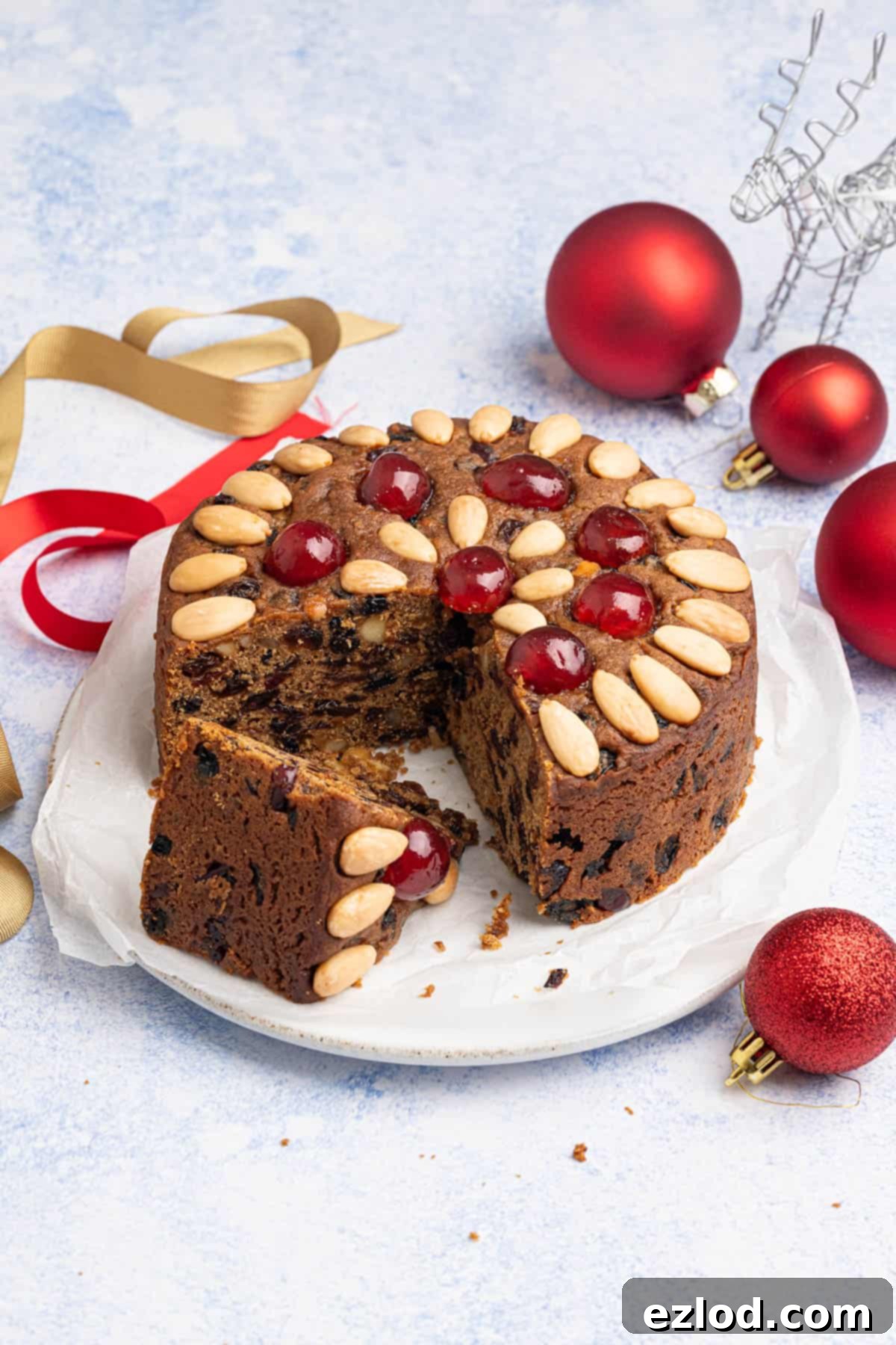 The sliced small batch vegan Christmas cake on a plate surrounded by festive decorations.