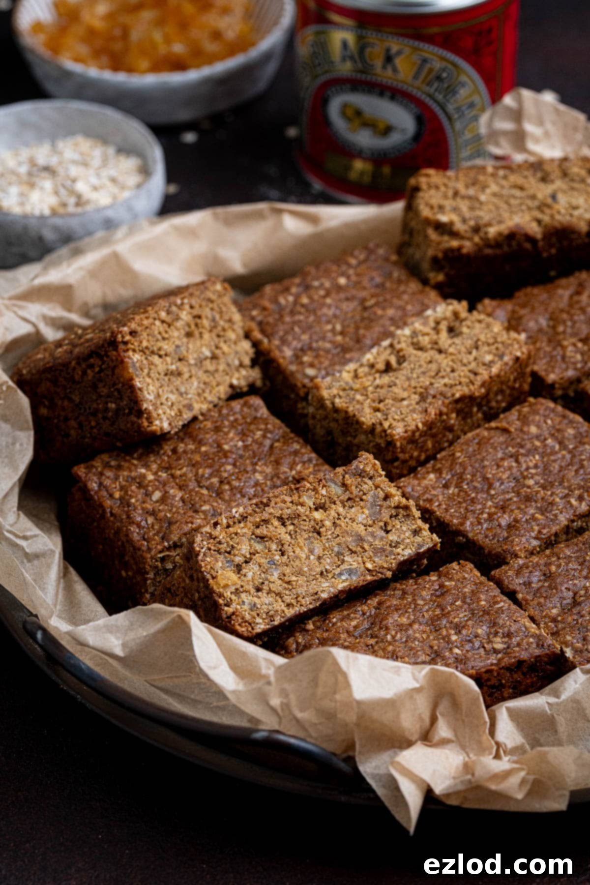Sliced vegan Thor cake on a tray with bowls of oats and candied peel and a tin of treacle in the background.