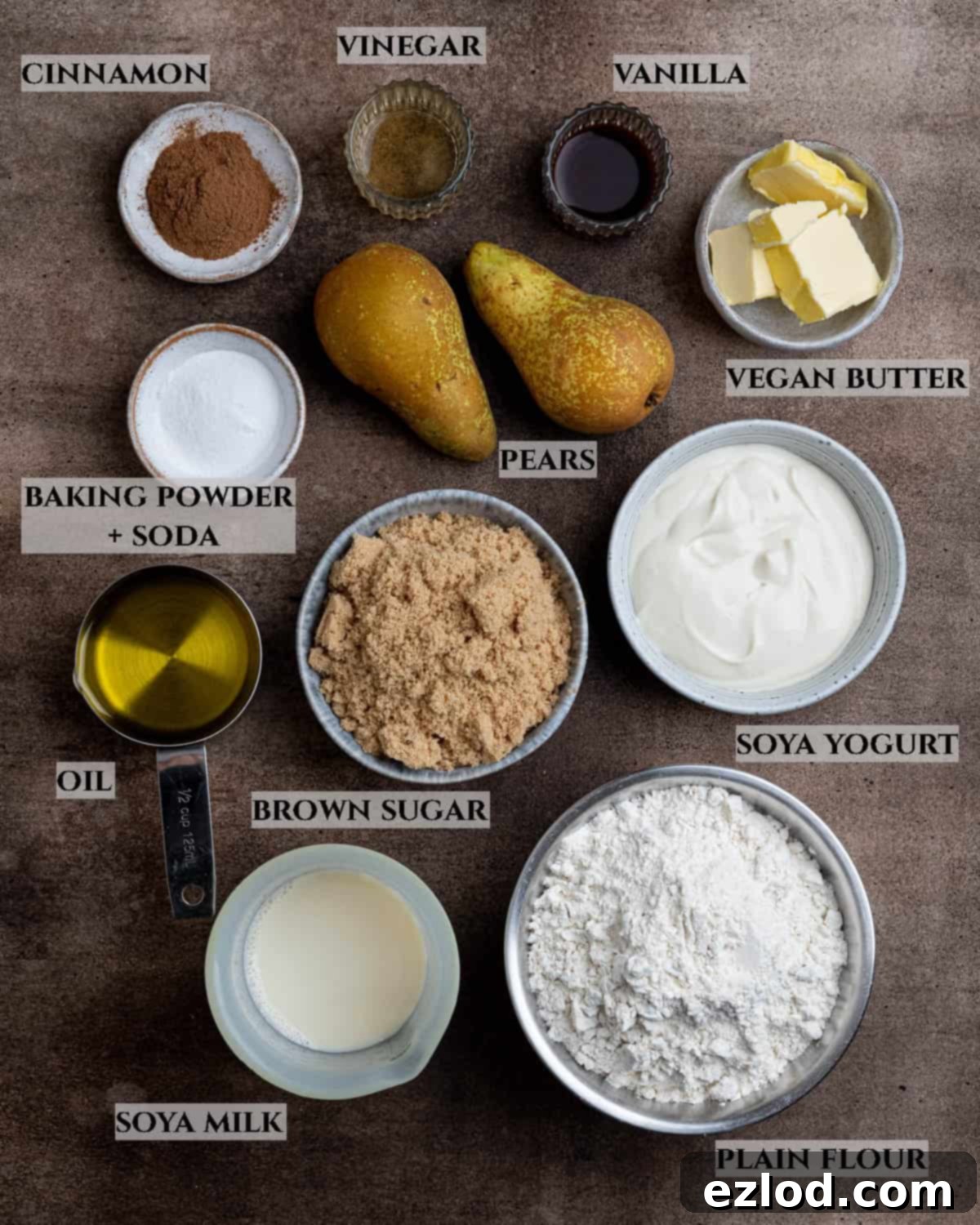Spiced Pear Plant-Based Muffins 3 A well-organized photo displaying all the ingredients required to bake vegan cinnamon pear muffins, including flour, sugar, oil, yogurt, milk, pears, and spices.
