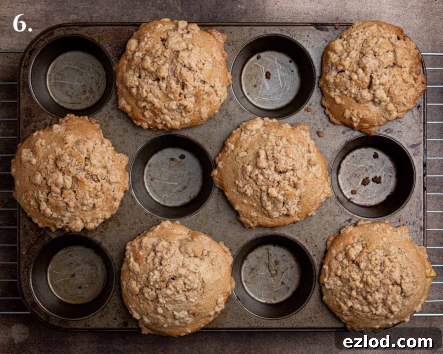 Spiced Pear Plant-Based Muffins 10 Step-by-step image of the freshly baked vegan cinnamon pear muffins, golden brown with crisp streusel toppings, cooling in the muffin tin.
