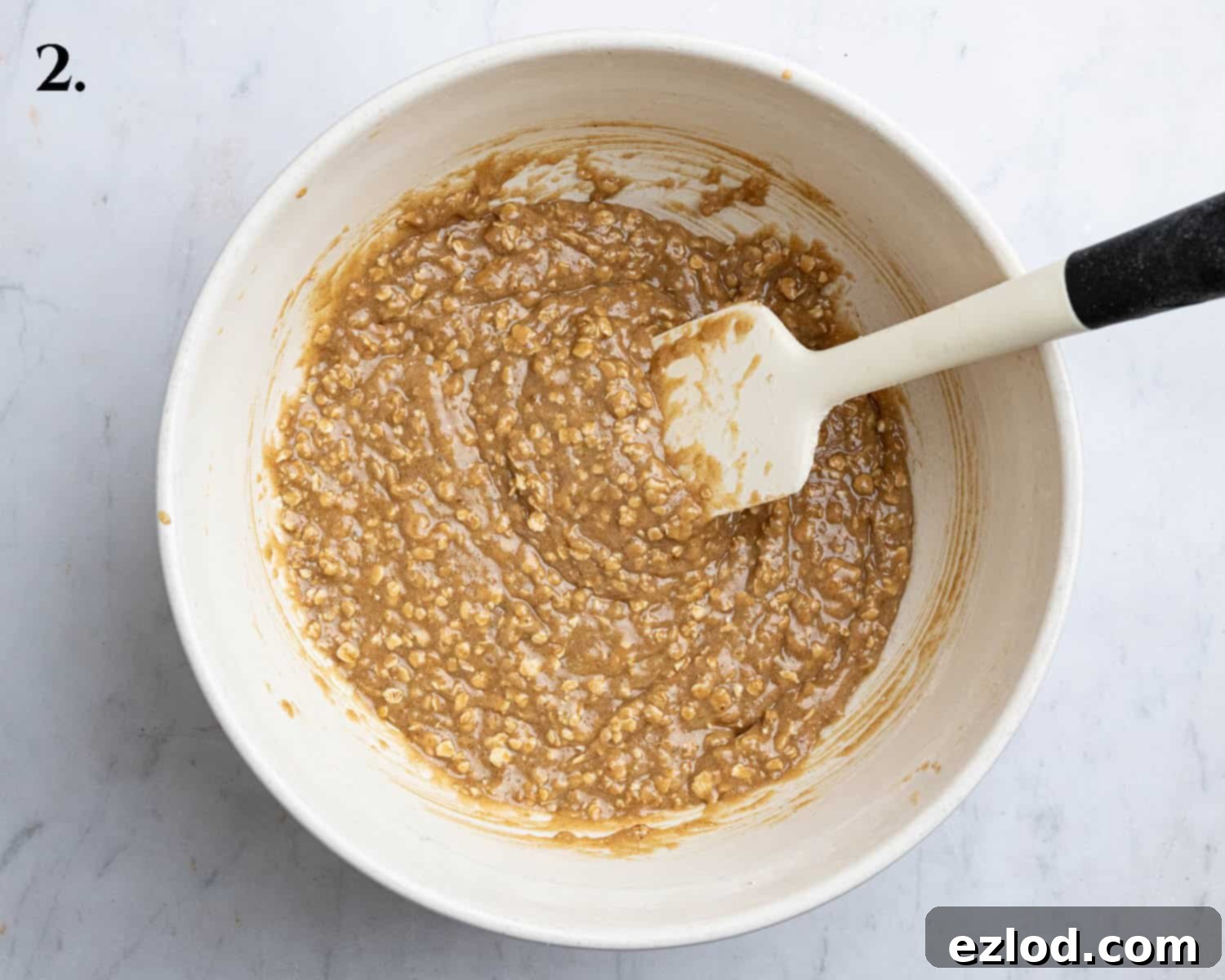 Step 2: The dry ingredients, including leavening agents, spices, oats, and flour, are mixed into the wet ingredients to form the cookie dough.