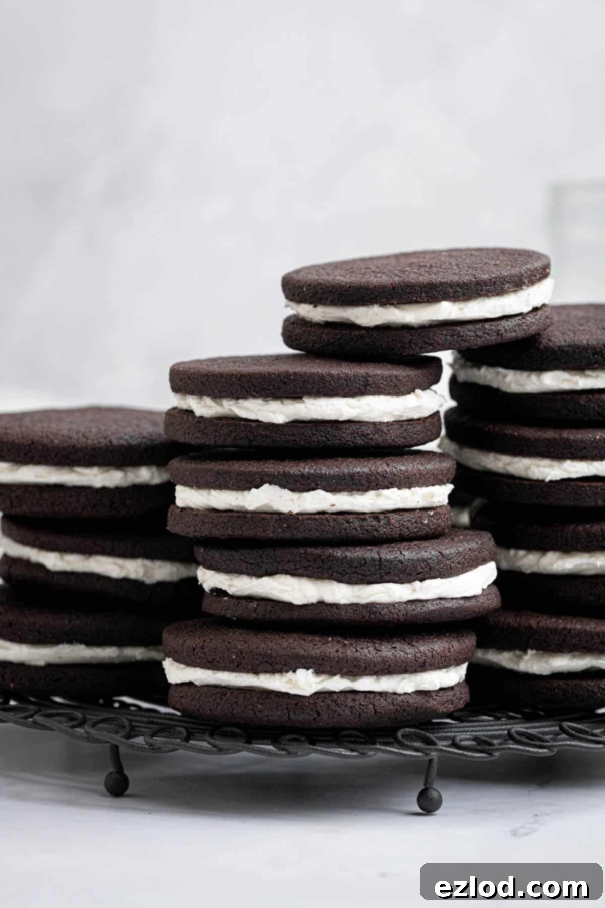 Multiple stacks of delicious vegan mint chocolate sandwich cookies cooling on a wire rack, showcasing their irresistible appeal.